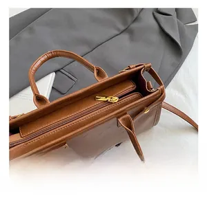 Detailed top view of brown textured leather handbag with gold zipper and internal compartments