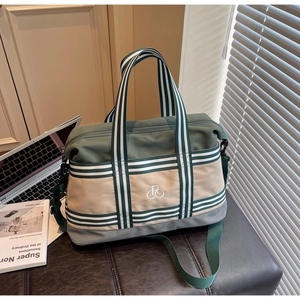 Détail du sac de voyage bicolore avec poignées rayées sur une surface texturée