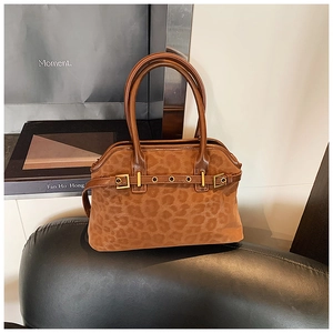 Detailed close-up of leopard print tote bag with gold metal buckle and dual handles
