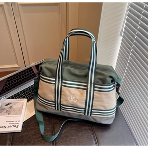 Détail du sac de voyage rayé vert armée avec bandoulière et logo brodé sur le devant