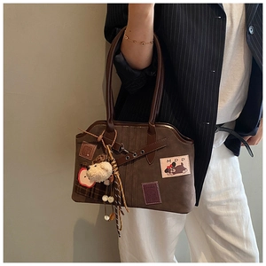 Detail of dark brown faux suede tote with cute cartoon patches and plush bear charm