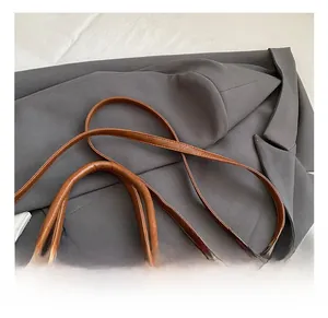 Close-up of adjustable leather shoulder strap and gold hardware on retro brown handbag