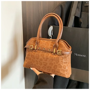 Detailed close-up of leopard print tote bag featuring a decorative belt buckle and gold eyelets