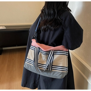 Détail du grand sac de voyage en toile tricolore avec anses rayées et broderie élégante