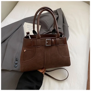 Detailed close-up of retro brown matte shoulder bag with leather straps and silver hardware