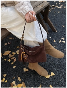 Detail of dark brown suede crescent bag with vintage wooden beads and clover charm pendant