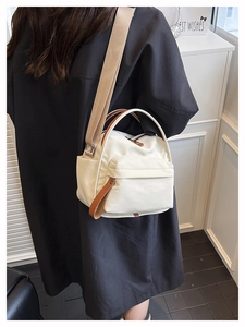 Detailed view of cream nylon tote bag with brown leather accents on a female model