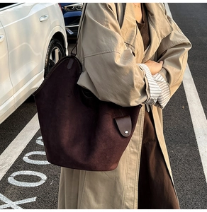 Detailed texture of a large burgundy suede tote bag with minimalist shoulder straps