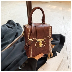 Detail of dark brown leather mini bag with gold T-lock and cute plush bear charm
