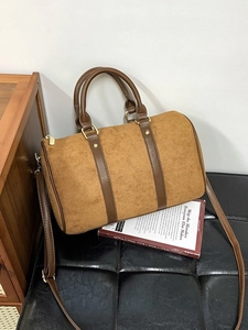 Retro brown faux suede Boston bag with gold hardware and adjustable strap on a chair