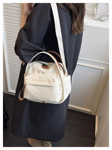 Detail of off-white canvas crossbody bag with dual zippers and adjustable wide strap