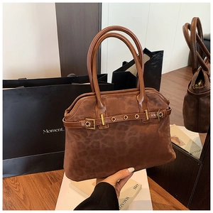 Detailed view of the leopard print suede texture and metallic buckle strap on the tote