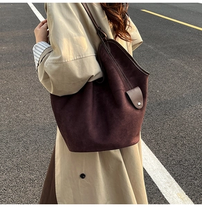 Detailed macro view of soft dark brown suede texture and metal buckle on the tote bag