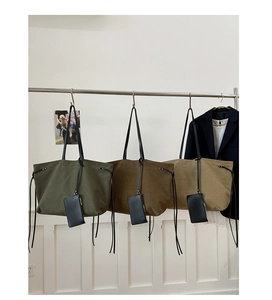 Detailed display of large canvas tote bags in olive, brown and khaki with tassel details