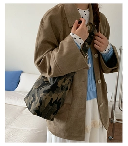 Detail of forest camouflage canvas shoulder bag worn by model in a cozy bedroom setting