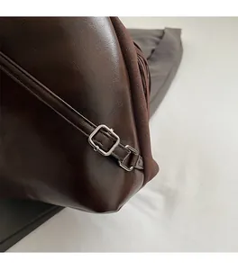 Detailed close-up of premium silver buckle and stitching on brown fringe backpack