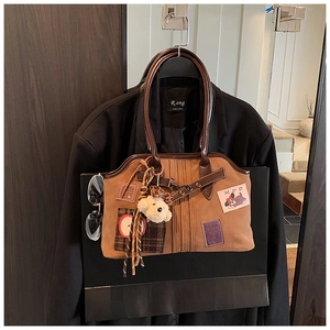 Detail of canvas and leather tote featuring apple embroidery and a plush puppy charm