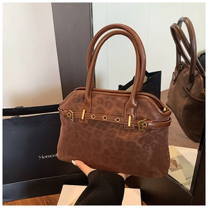 Detail of leopard print tote bag with brown leather handles and gold buckle hardware