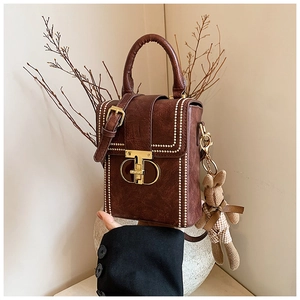 Close-up of brown vintage structured handbag with gold clasp and decorative white beads