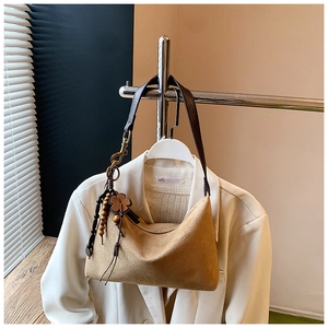 Detail of suede crescent shoulder bag with vintage wood bead and leather clover charm