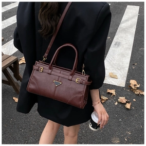 Detail of a vintage coffee brown leather handbag with metallic triangle logo and street view