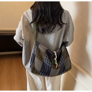 Détail du sac à carreaux vintage avec nœud de corde et patch en cuir cœur vert