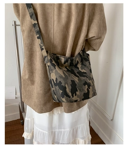 Detail of military camouflage canvas hobo bag with wide shoulder strap worn by model