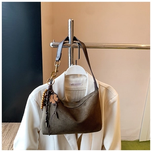Close-up of suede hobo bag with leather strap, gold hardware and clover pendant detail