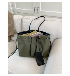 Detailed macro view of army green canvas tote bag with black leather straps on sofa