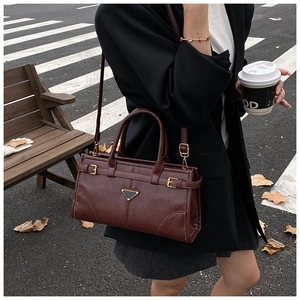 Detail of dark brown vintage faux leather handbag with metal triangle and strap accents