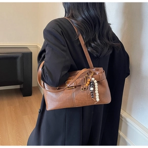 Detail view of vintage brown leather bag with buckle strap and tricolor beaded pendant