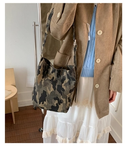 Detail of camouflaged canvas tote bag featuring wide shoulder straps and large capacity