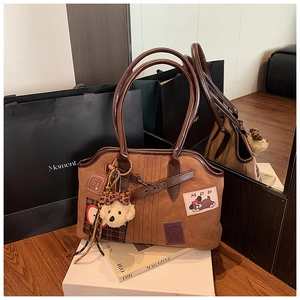 Detail of vintage brown tote bag with cute apple embroidery and plush bear charm