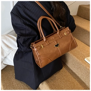 Detail of vintage brown leather handbag with gold buckles and triangle metal logo