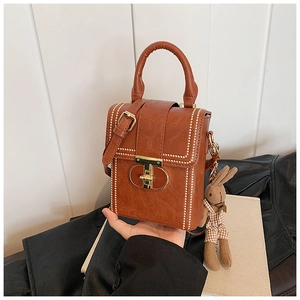 Detailed shot of brown vintage handbag with gold clasp and cute rabbit doll charm