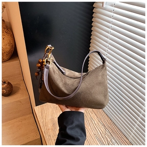 Detail of tan suede dumpling bag with dark leather strap and vintage wooden bead pendant