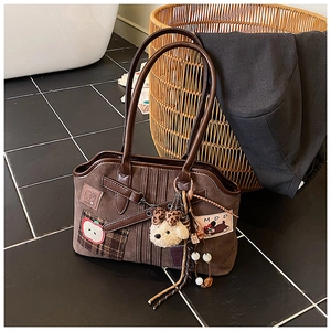 Close-up of vintage brown suede tote bag with apple embroidery and plush charms
