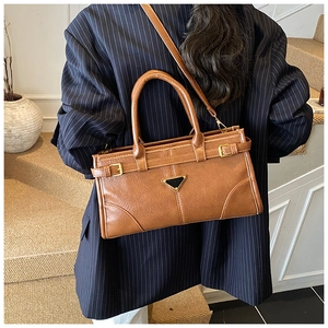 Detail of a brown leather handbag with a triangle logo and dual top handles on a model