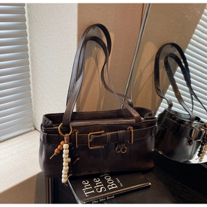 Detail of vintage brown shoulder bag with gold buckle and unique beaded tassel decoration