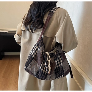 Détail du sac hobo vintage à carreaux avec cordon de serrage tissé sur un trench-coat kaki