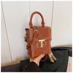Detail of a brown PU leather phone bag featuring a gold T-lock and cute bear charm
