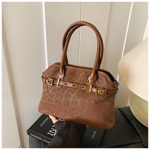 Detailed view of leopard print texture and golden buckle strap on brown tote bag