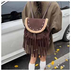 Detail of a brown fringe backpack with star rivets and wool trim in an autumn outdoor setting