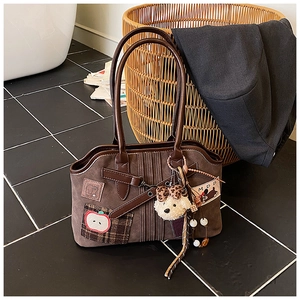 Detail of dark brown tote bag with apple embroidery, teddy bear charm, and beads