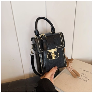 Close-up of a vintage black mini handbag featuring gold studs and a geometric metal lock