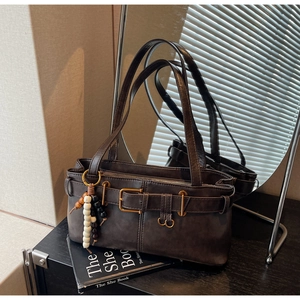 Detail of dark brown vintage faux leather shoulder bag with buckle and bead charm