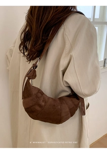 Close-up of brown suede croissant bag worn by model showing segment stitching and retro style