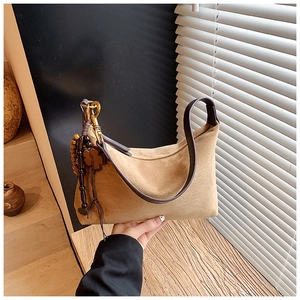 Detail of vintage suede shoulder bag with bronze hardware and decorative clover charm