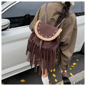 Detail view of brown backpack featuring silver star studs, lamb wool trim and long tassels