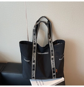 Detailansicht der großen schwarzen Segeltuchtasche mit floralem Gurt und Seitentasche